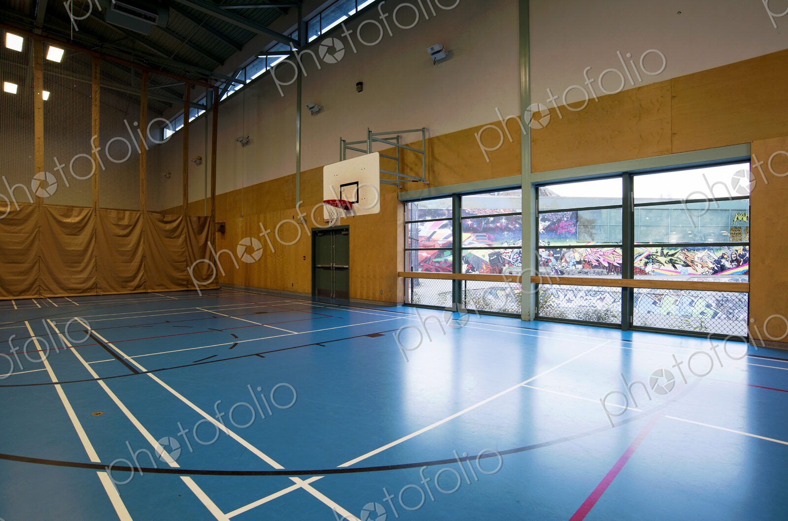 Spacious gymnasium with a basketball court floor markings, light and airy, glass doors