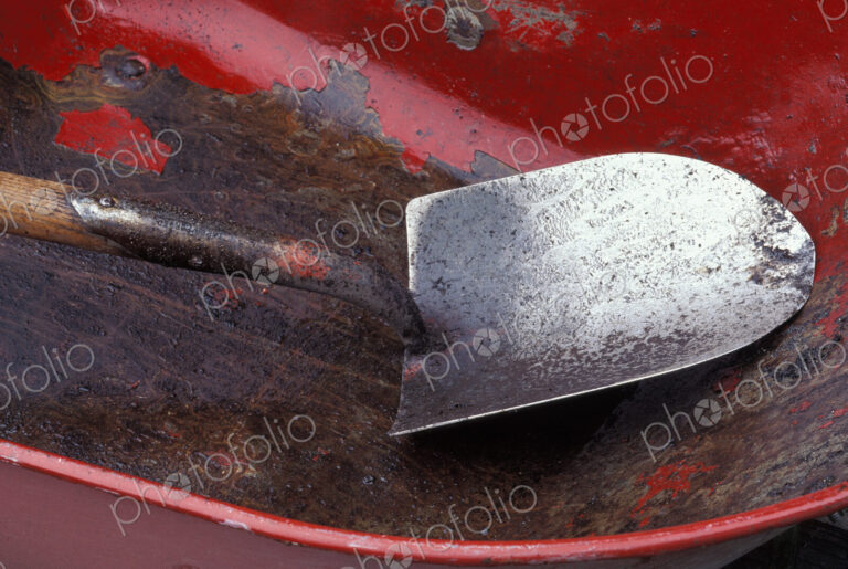 Spade in an empty red wheelbarrow.