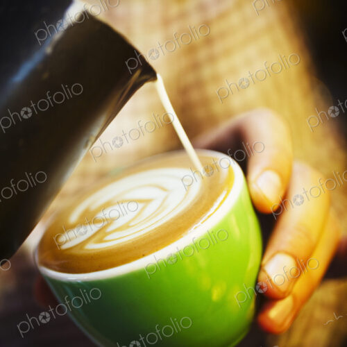 Specialist coffee shop. A barista creating a pattern in the froth on a cup of coffee.