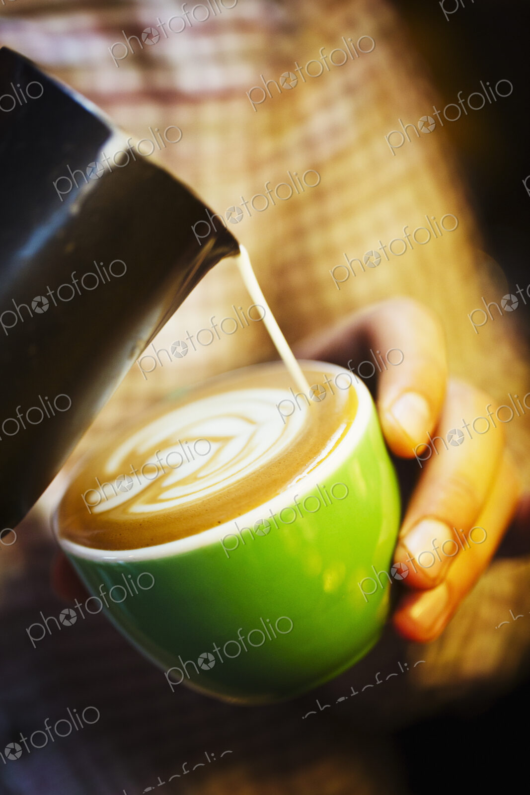 Specialist coffee shop. A barista creating a pattern in the froth on a cup of coffee.