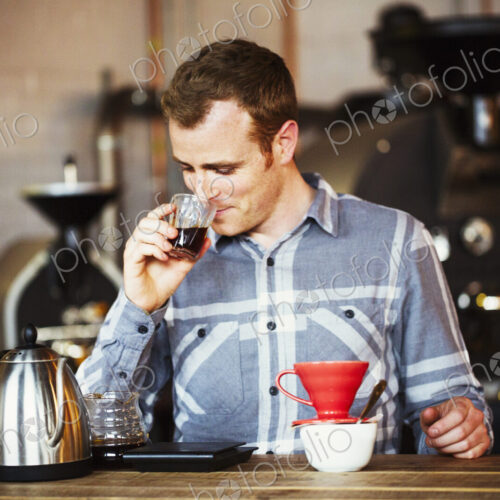 Specialist coffee shop. A man brewing coffee using a filter paper, and drinking it. Specialist coffee shop. A man brewing coffee using a filter paper, and drinking it.