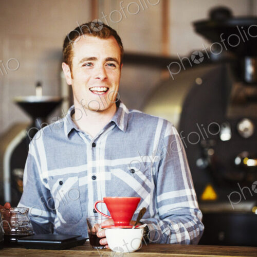 Specialist coffee shop. A man brewing coffee using a filter paper, and drinking it.