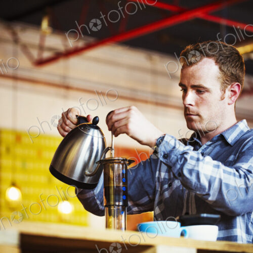 Specialist coffee shop. A man pouring hot water into a coffee perculator. Specialist coffee shop. A man pouring hot water into a coffee perculator.