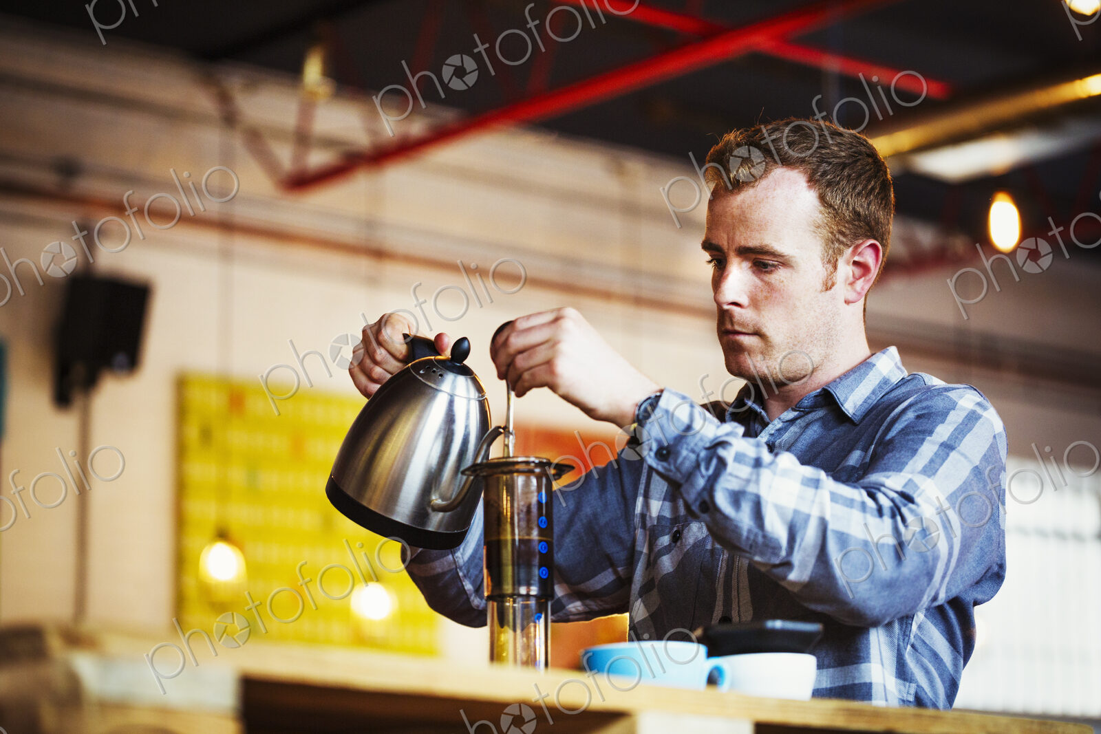 Specialist coffee shop. A man pouring hot water into a coffee perculator.