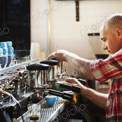 Specialist coffee shop. A man working a coffee machine making coffee. Specialist coffee shop. A man working a coffee machine making coffee.