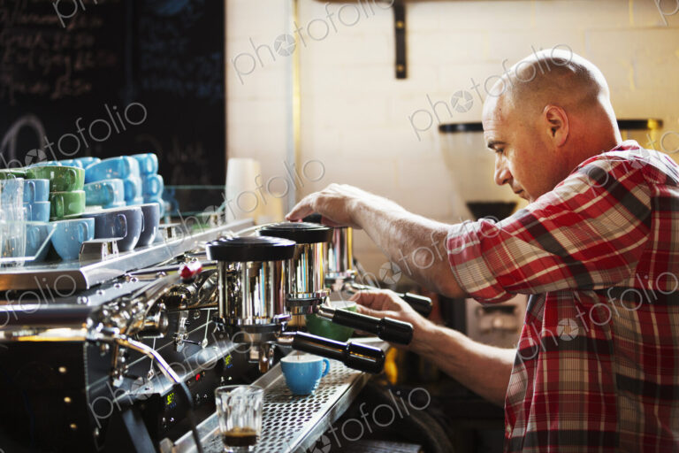 Specialist coffee shop. A man working a coffee machine making coffee.