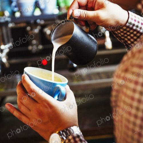 Specialist coffee shop. A person making coffee and pouring milk into a cup held at an… Specialist coffee shop. A person making coffee and pouring milk into a cup held at an…