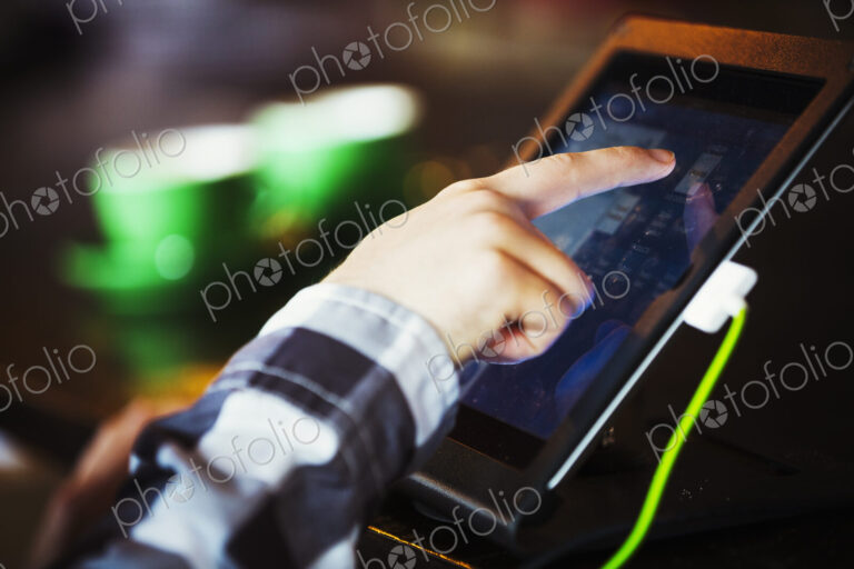 Specialist coffee shop. A person using a touch screen at a till.