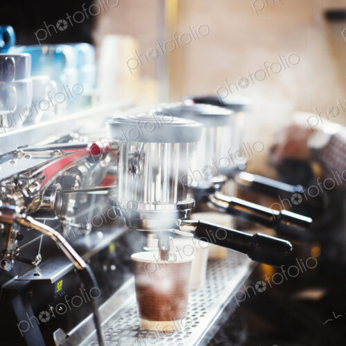 Specialist coffee shop. A person working at a large coffee machine, with three… Specialist coffee shop. A person working at a large coffee machine, with three…