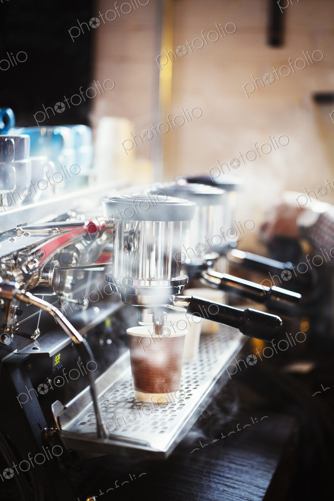 Specialist coffee shop. A person working at a large coffee machine, with three…