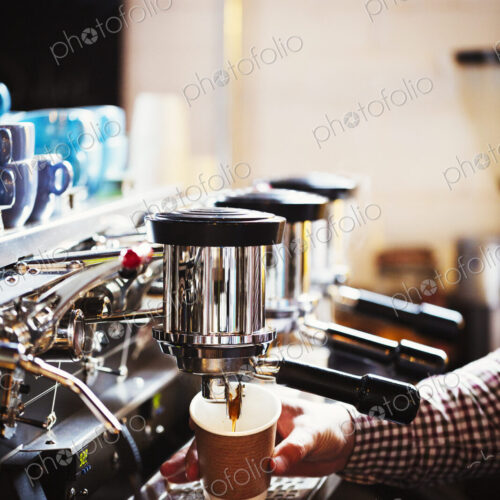 Specialist coffee shop. A person working at a large coffee machine, with three… Specialist coffee shop. A person working at a large coffee machine, with three…