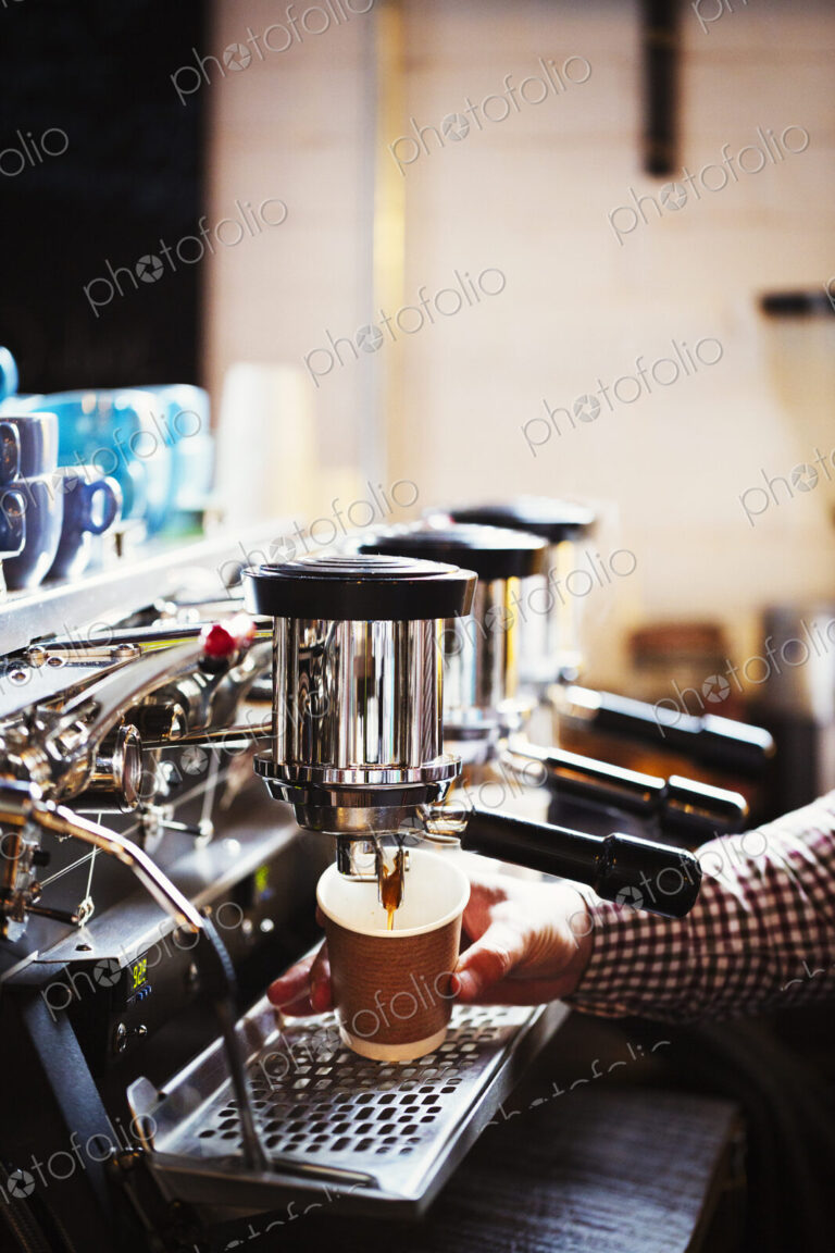 Specialist coffee shop. A person working at a large coffee machine, with three…
