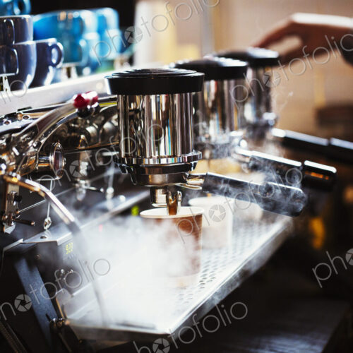 Specialist coffee shop. A person working at a large coffee machine, with three… Specialist coffee shop. A person working at a large coffee machine, with three…