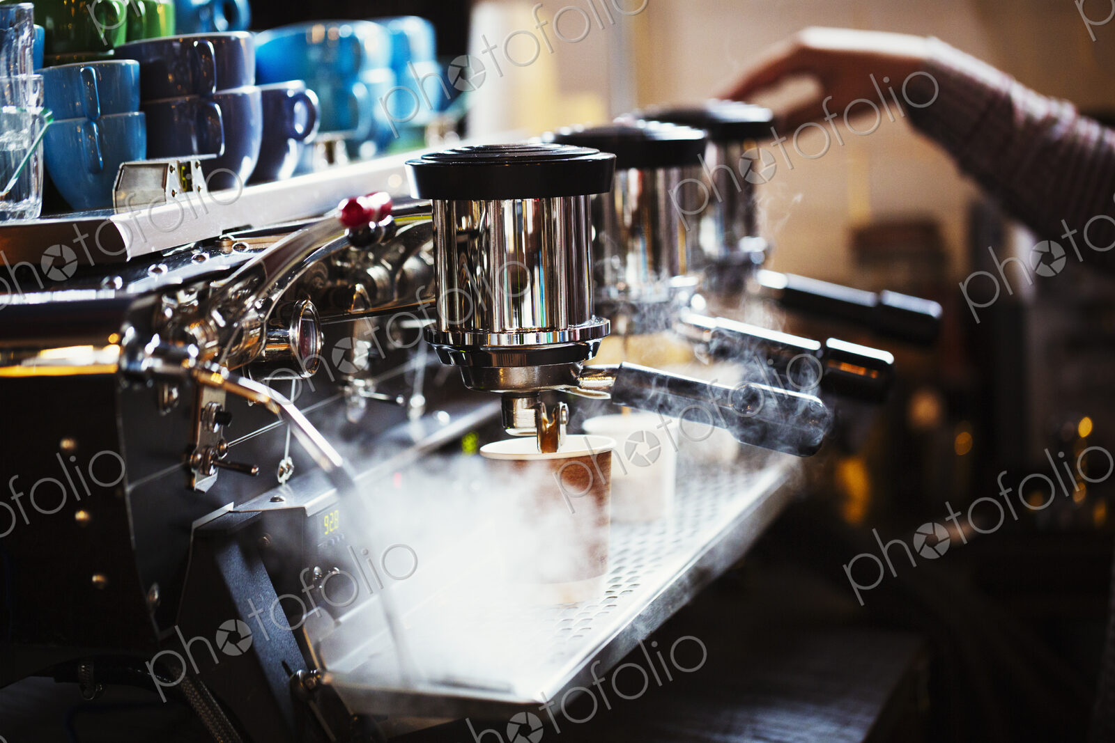 Specialist coffee shop. A person working at a large coffee machine, with three…