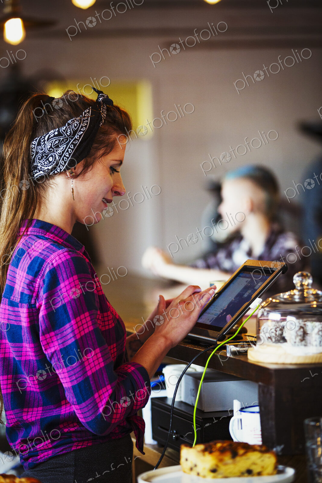 Specialist coffee shop. A woman working behind the counter using the touch screen on…
