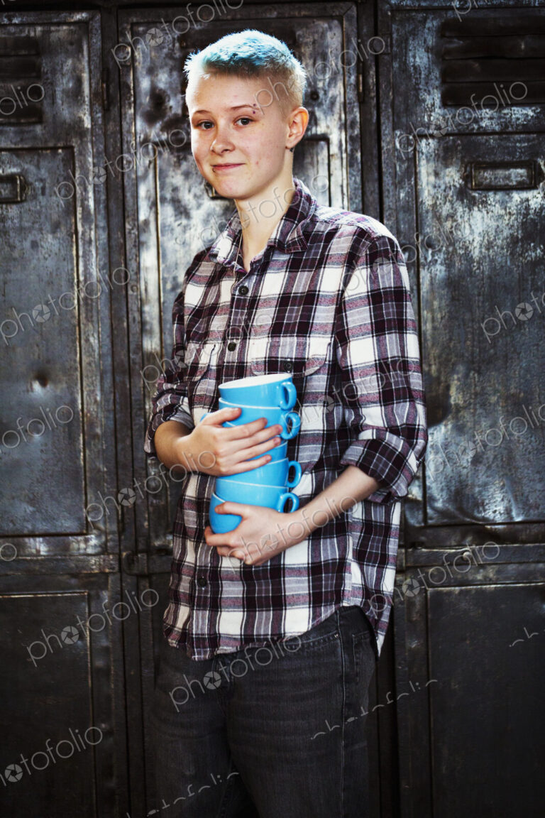 Specialist coffee shop. A young girl carrying a stack of blue coffee cups.