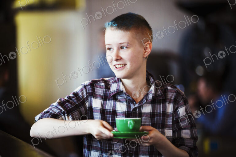 Specialist coffee shop. A young persion carrying a cup of coffee.