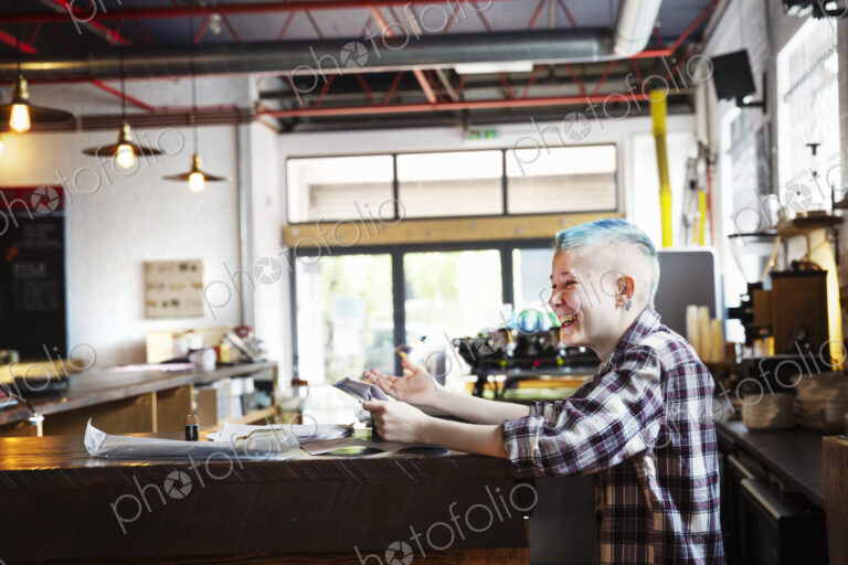 Specialist coffee shop. A young person seated at a counter laughing.