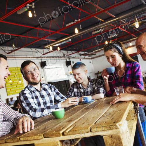 Specialist coffee shop. Five people seated around a wooden table. Specialist coffee shop. Five people seated around a wooden table.