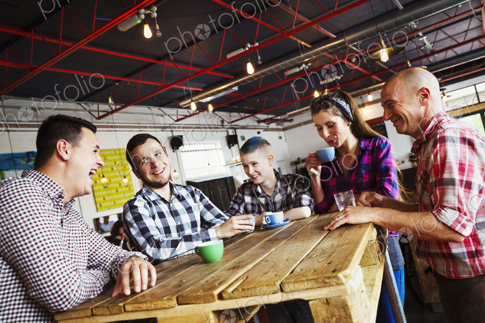Specialist coffee shop. Five people seated around a wooden table.