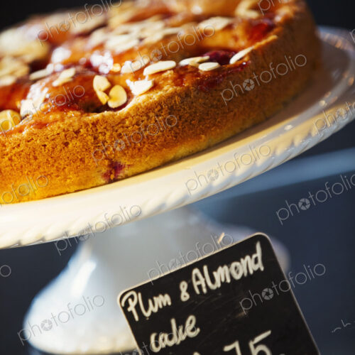 Specialist coffee shop. Plum and almond cake on a cake stand. Specialist coffee shop. Plum and almond cake on a cake stand.