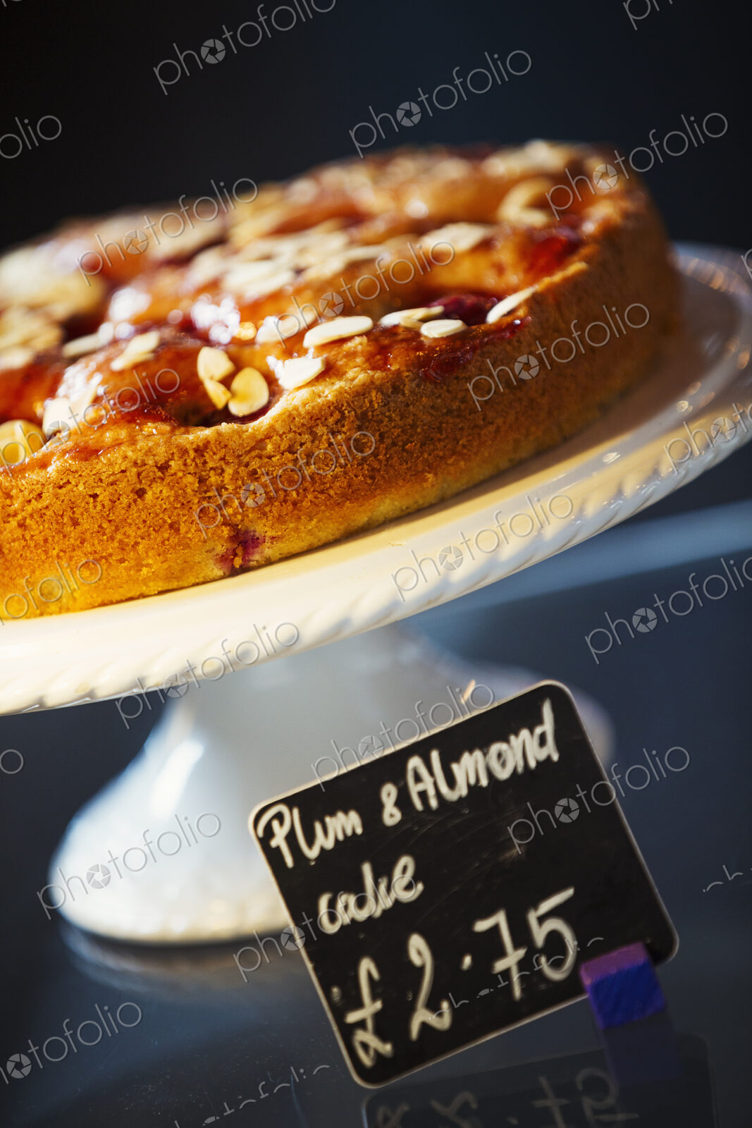 Specialist coffee shop. Plum and almond cake on a cake stand.
