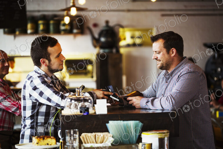 Specialist coffee shop. Two men, a barista and a client talking over the coffee shop…