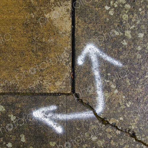 Spray painted arrows on broken pavement