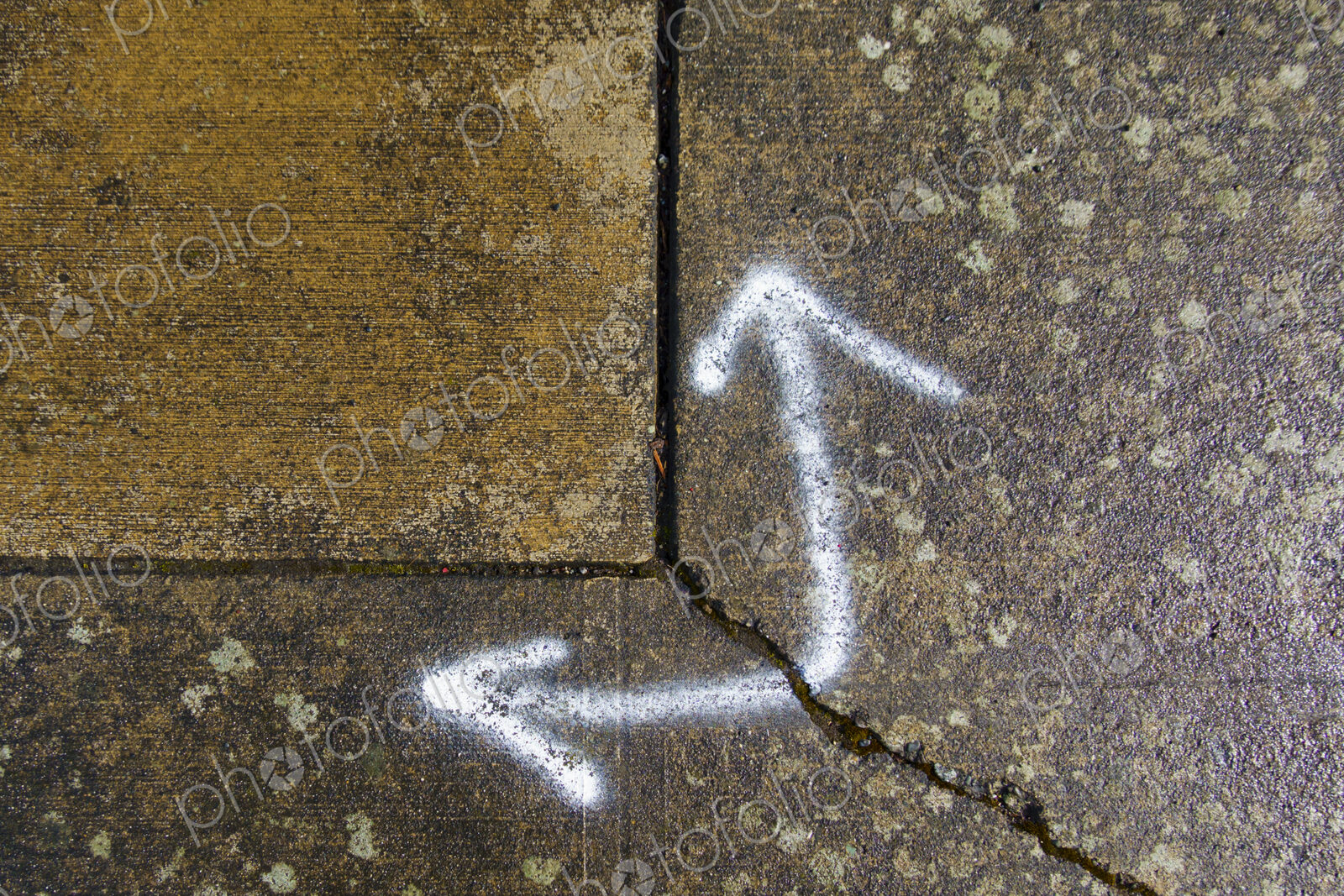 Spray painted arrows on broken pavement