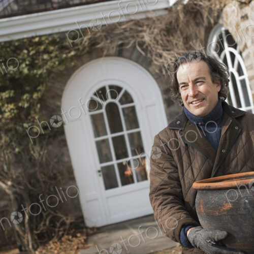 Spring Planting. A man carrying a large terracotta pot across a courtyard. Spring Planting. A man carrying a large terracotta pot across a courtyard.