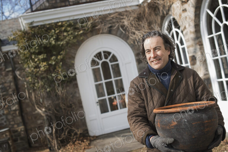 Spring Planting. A man carrying a large terracotta pot across a courtyard.