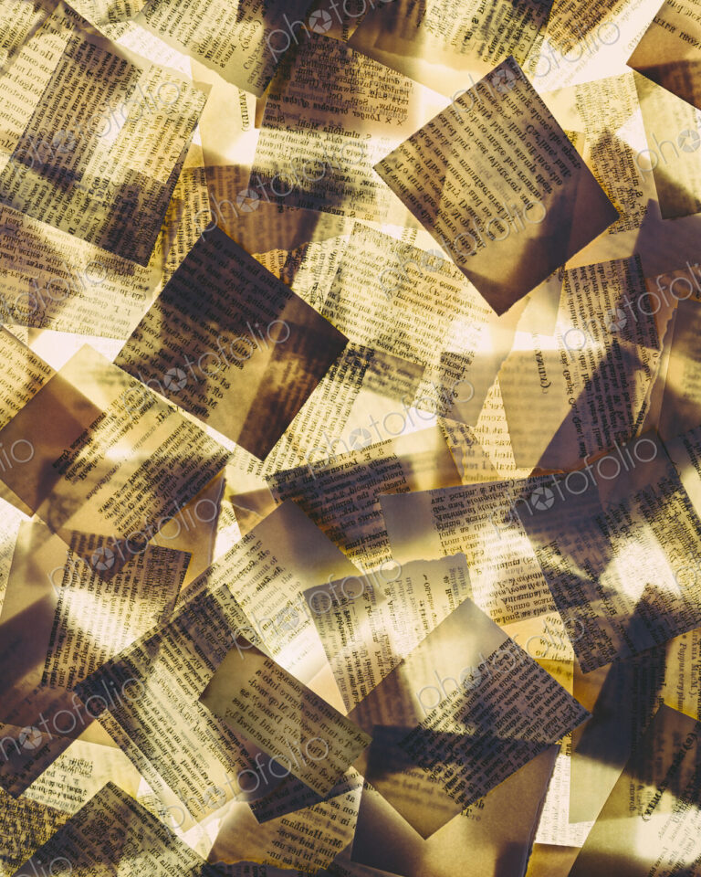 Squares of overlapping pieces of paper from old books, lit from below. Printed pages,…