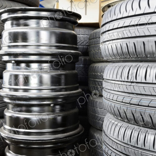Stack of car tyres and wheel rims in an auto repair shop garage.