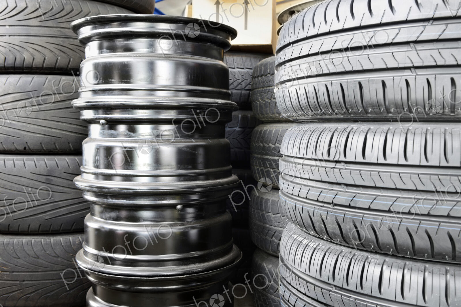 Stack of car tyres and wheel rims in an auto repair shop garage.