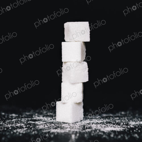 Stack of sugar cubes, balancing one on top the other, on black backdrop Stack of sugar cubes, balancing one on top the other, on black backdrop