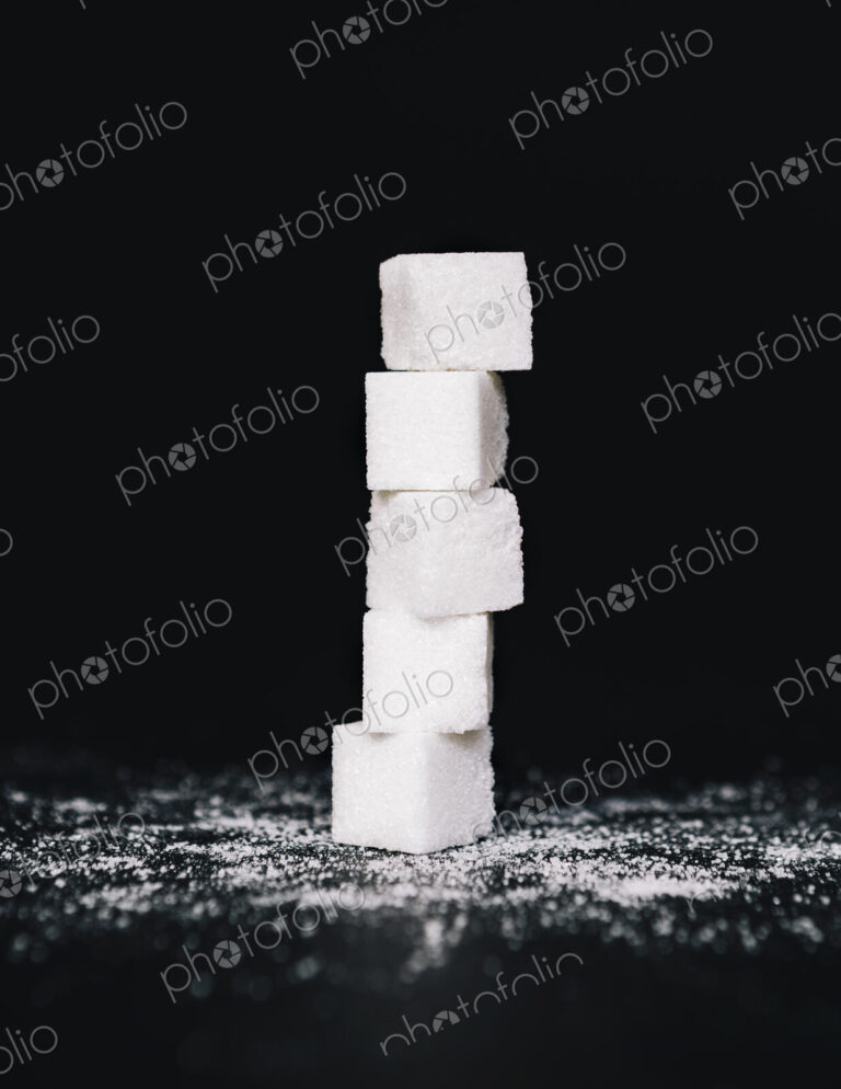 Stack of sugar cubes, balancing one on top the other, on black backdrop