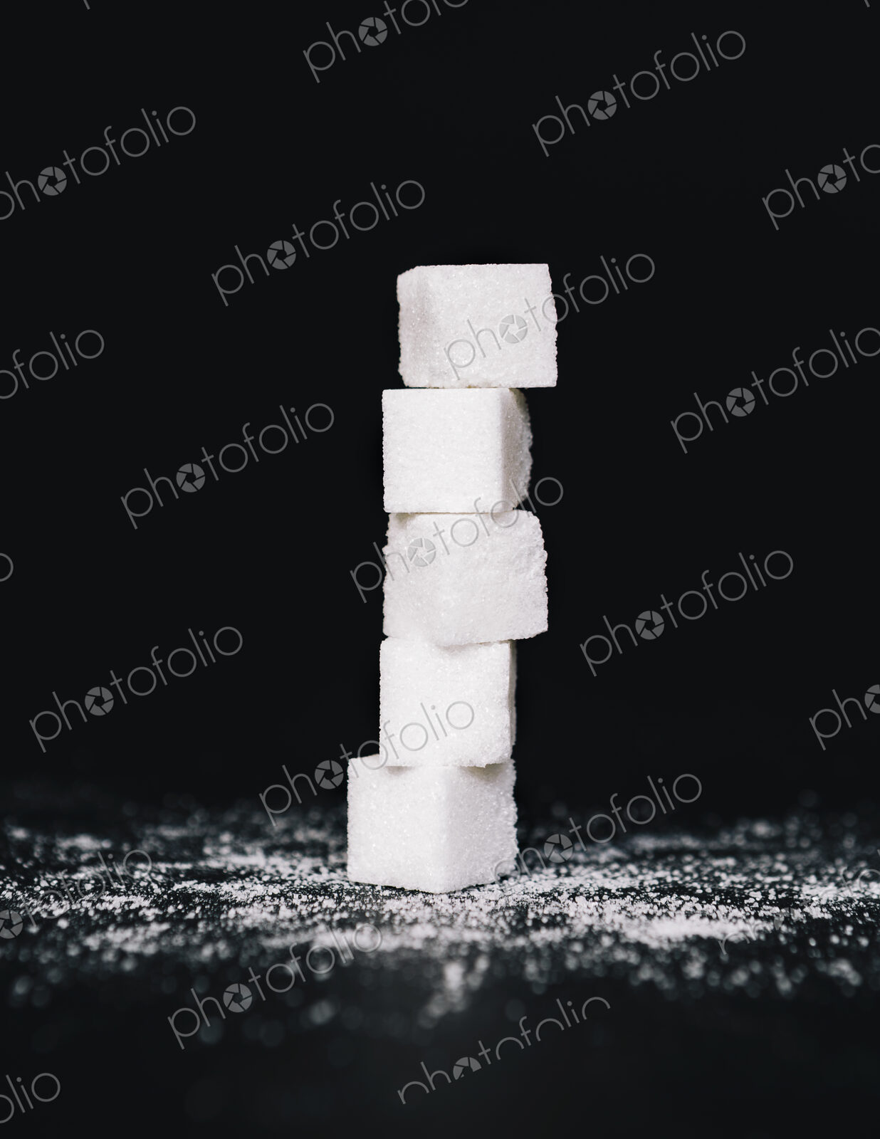 Stack of sugar cubes, balancing one on top the other, on black backdrop