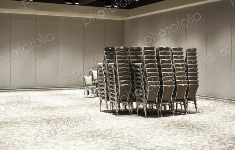 Stacked chairs in an empty convention center meeting room.