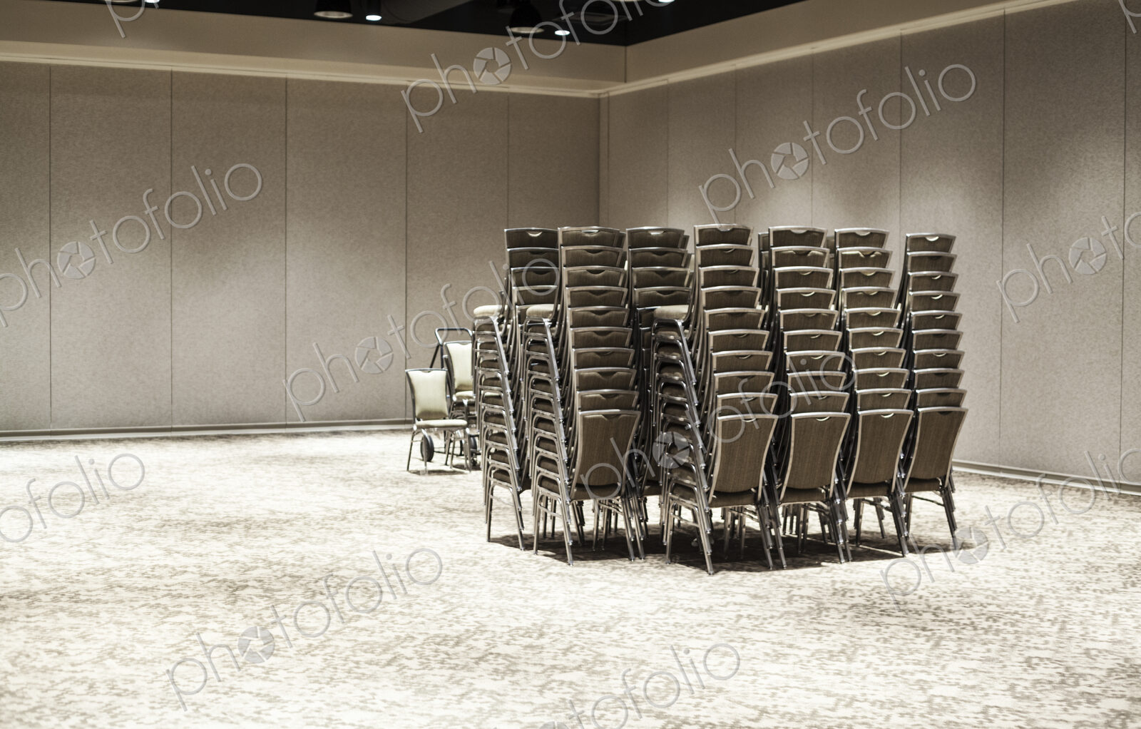 Stacked chairs in an empty convention center meeting room.