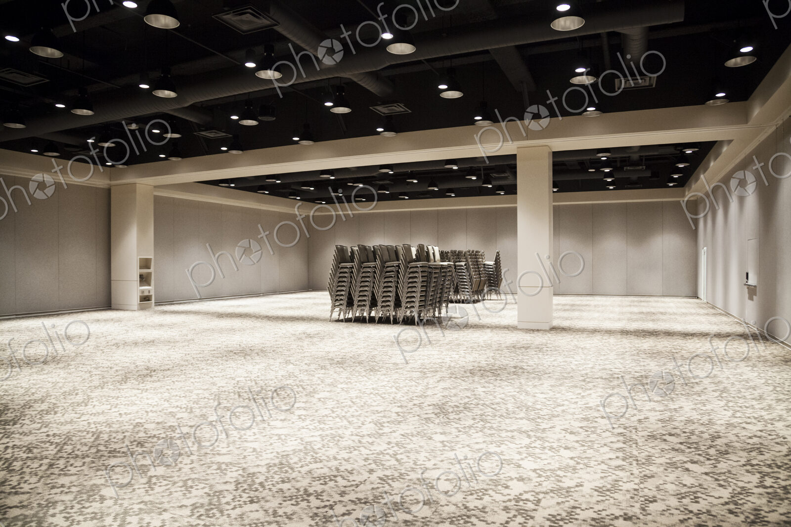 Stacked chairs in an empty convention center meeting room.