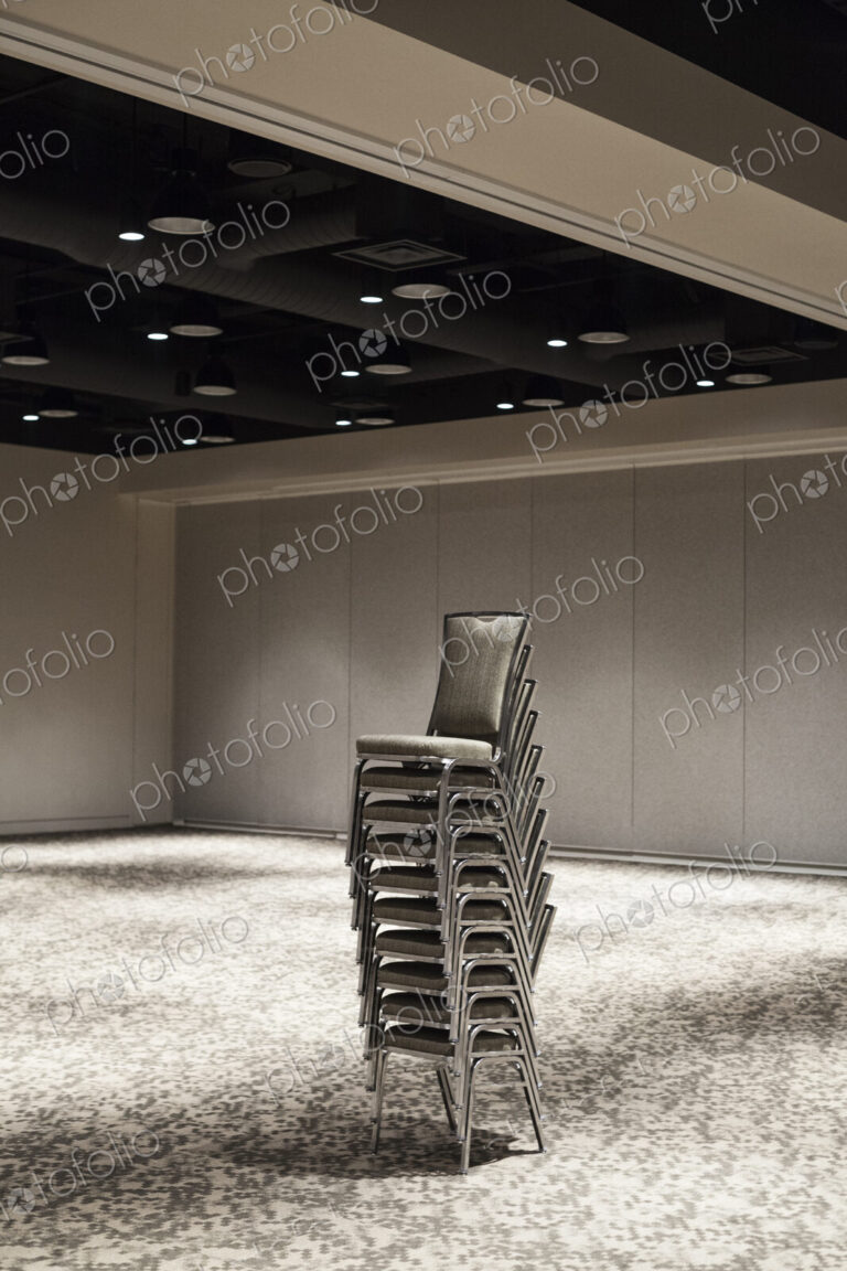Stacked chairs in an empty convention center meeting room.