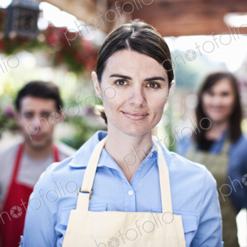 Staff of a garden center nursery with a caucasian woman employee in the lead.