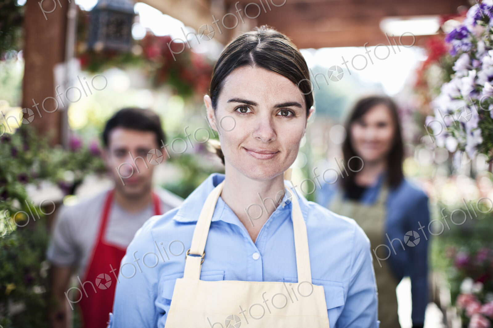 Staff of a garden center nursery with a caucasian woman employee in the lead.