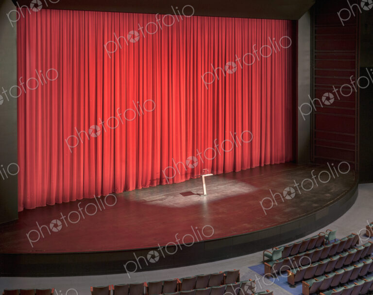 Stage with red curtains in an empty auditorium.