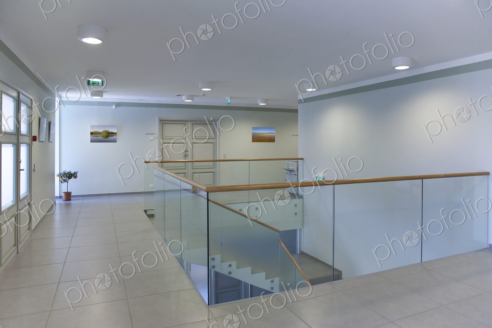 Stairwell and open plan room with large windows and light airy feel, glass balustrade.