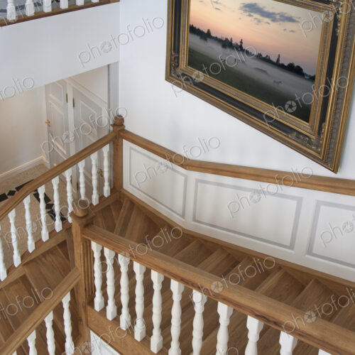 Stairwell in a house with traditional wooden bannisters and oil painting on wall