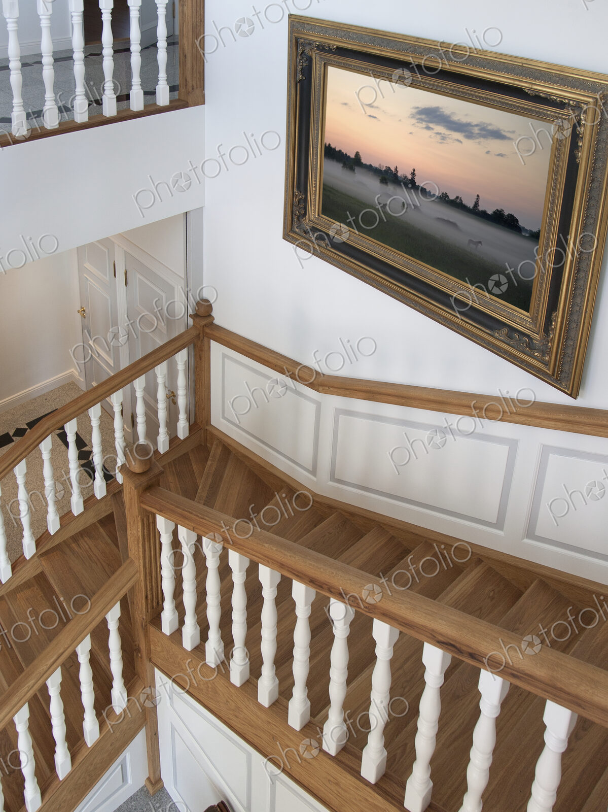 Stairwell in a house with traditional wooden bannisters and oil painting on wall
