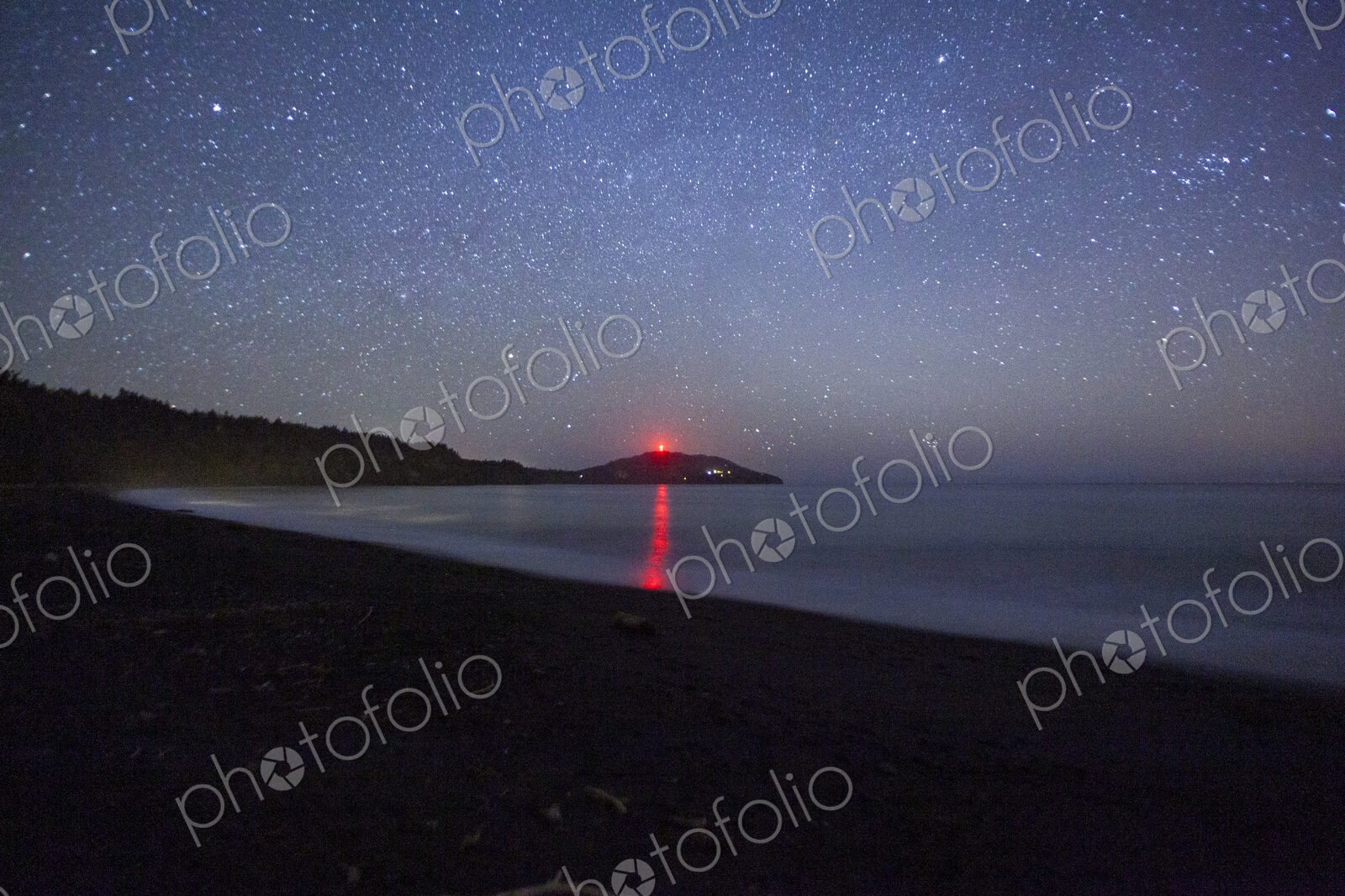 Star filled sky above Freshwater Bay, Port Angeles, the orange sun on the horizon.