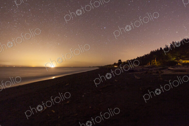 Star filled sky and the sun emerging on the horizon above Freshwater Bay, Port Angeles