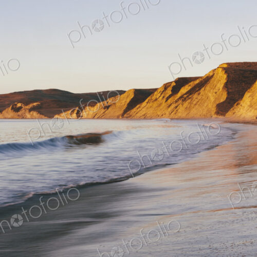 Steep cliffs and beach with surf at dawn
